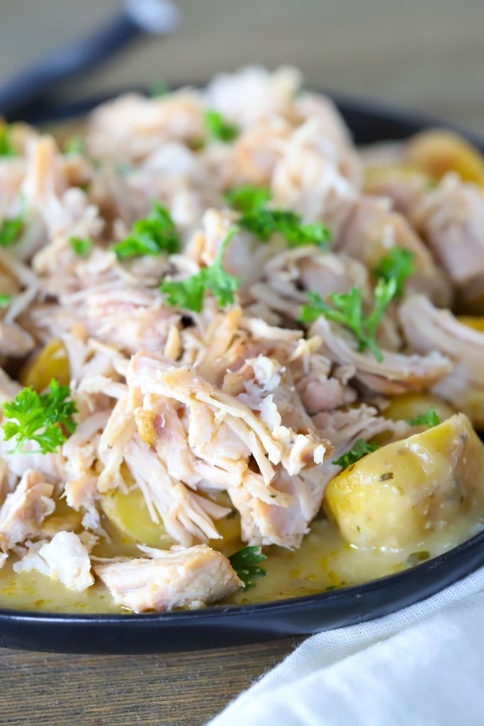 pork chops and potatoes on a black plate with silverware behind.