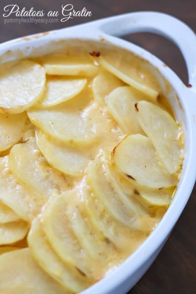 Cheesy Potatoes au Gratin made with a homemade cheese sauce drizzled over thinly sliced potatoes and a layer of onions nestled in the middle. A great Thanksgiving recipe! Plus a full blog hop Thanksgiving menu to help plan your turkey day meal!