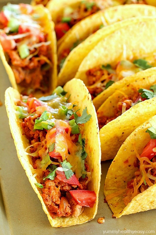 Ground Turkey Tacos that are oven-baked with layers of deliciousness inside! Refried beans, ground turkey taco meat, (no taco seasoning mix!) tomato, cilantro, green onions and cheese all baked in taco shells. Perfect for Taco Tuesday or for game day! AD