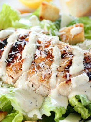 Grilled Chicken Caesar Salad for a yummy summertime lunch or dinner! With a simple yogurt marinade recipe, this grilled chicken is tender and delicious. Served over romaine lettuce, homemade croutons, shaved parmesan and caesar dressing - YUM!!