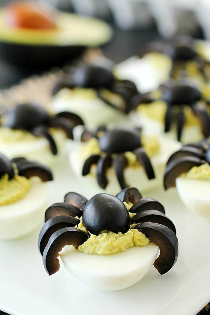 Celebrate Halloween with Spooky Spider Avocado Deviled Eggs! Your party guests will love these creepy crawly olive spiders on top of ghoulishly green avocado deviled eggs!