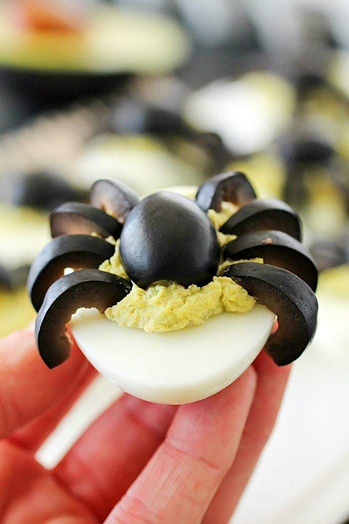 Celebrate Halloween with Spooky Spider Avocado Deviled Eggs! Your party guests will love these creepy crawly olive spiders on top of ghoulishly green avocado deviled eggs!