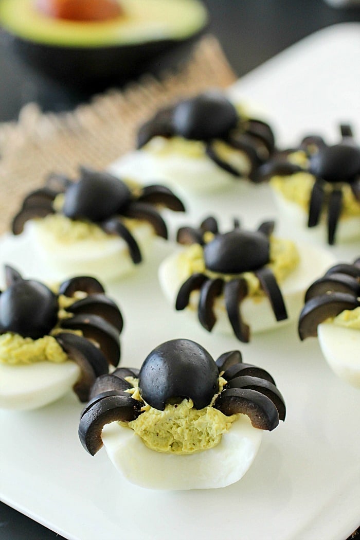 Celebrate Halloween with Spooky Spider Avocado Deviled Eggs! Your party guests will love these creepy crawly olive spiders on top of ghoulishly green avocado deviled eggs!