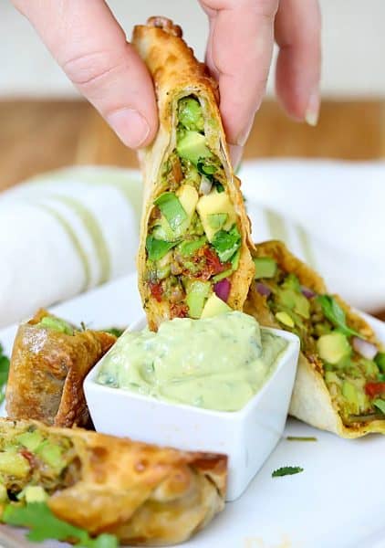 Photo of a sliced Homemade Avocado Southwest Egg Roll being dipped into an Avocado Dip. Yum!