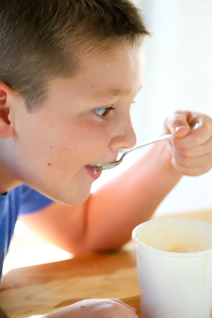8 year old Tate Nikolaus eating a spoon of frozen yogurt with a happy look on his face!