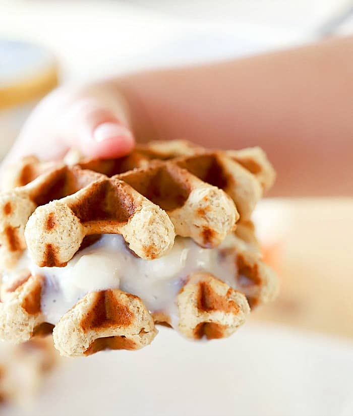 Child's hand holding a melty sandwich on a bright day.