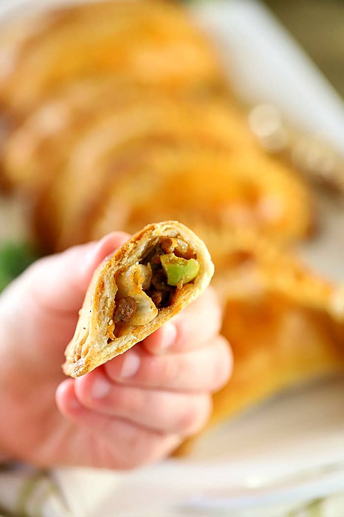 A little hand holding a sliced in half empanada