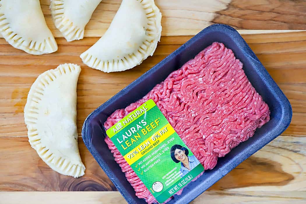 Overhead picture of Laura's Lean Ground Beef and four uncooked empanadas