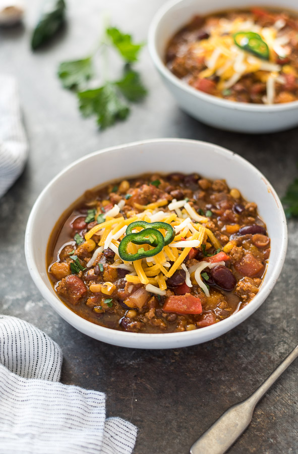 Two bowls of pumpkin chili topped with cheese and jalapeños.