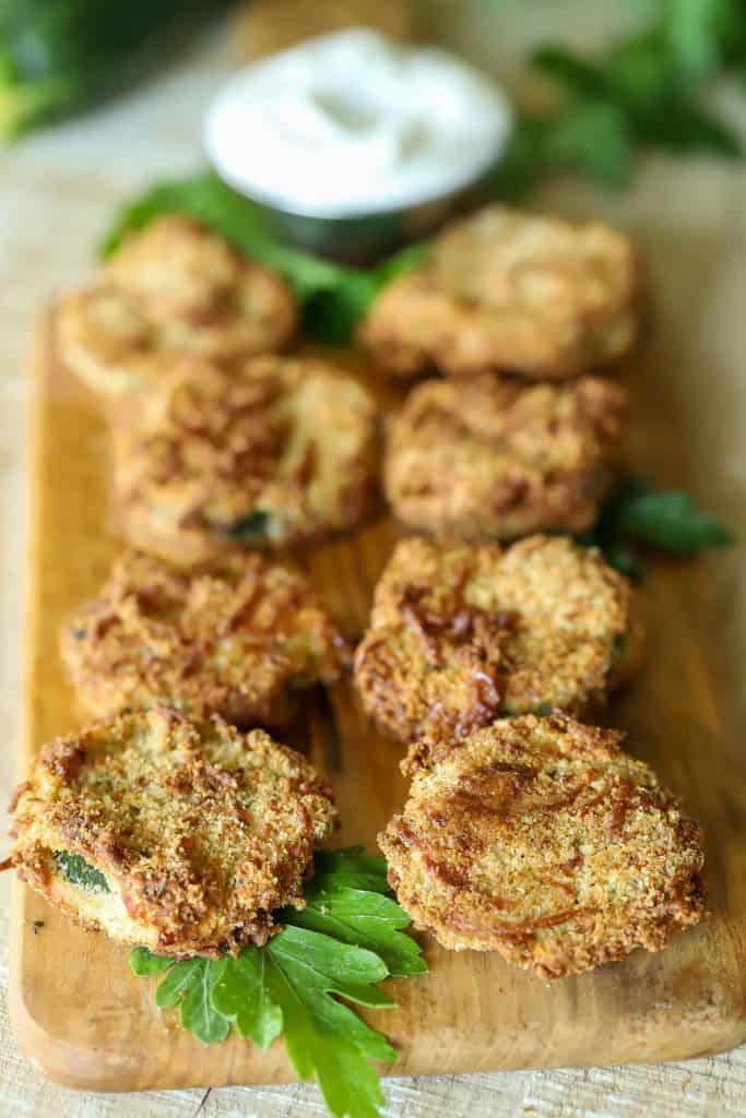 Platter of yummy breaded zucchini chips with a dipping sauce on the side.