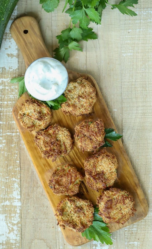 Overhead shot of Zucchini Chips with a dipping sauce on a cutting board.